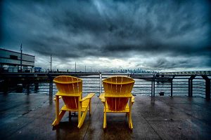 two Adironcack chairs on a waterfront deck