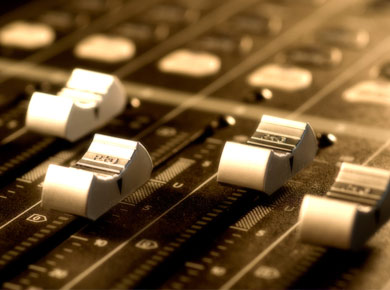 close up of audio faders on a mixing board